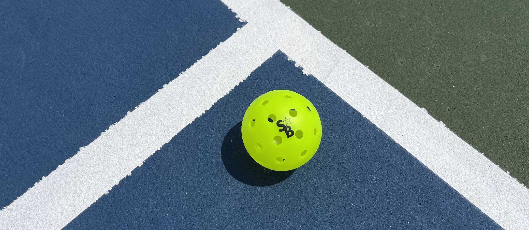 A pickleball ball on a pickleball court.