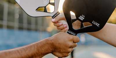 Two players holding their pickleball paddles together