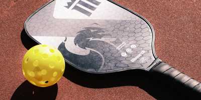 A pickleball paddle and ball on a court