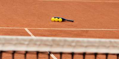 Three pickleballs underneath a pickleball paddle